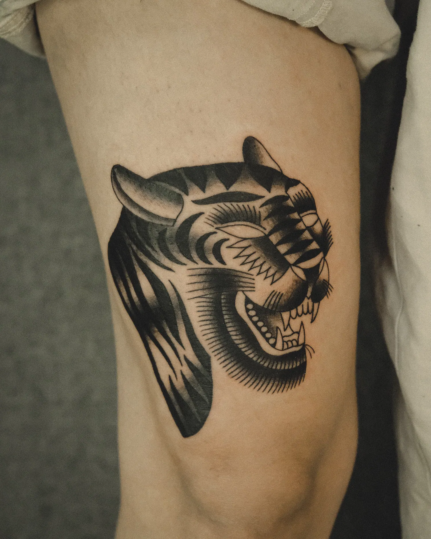 A bold black tiger head tattooed on the upper arm