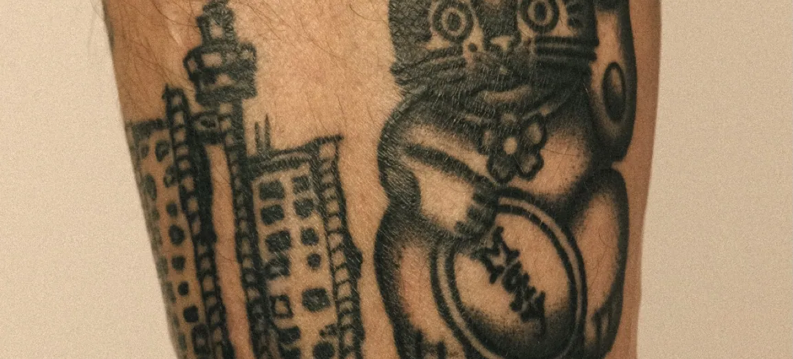 Two healed tattoos on a forearm, a tower and a lucky cat